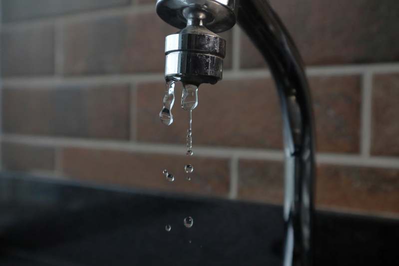 Blogger measuring water flow and latency response of a smart faucet during in-kitchen testing