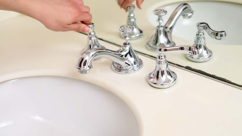 Close-up of a brushed nickel smart faucet with digital temperature display and motion sensor indicator lit in blue